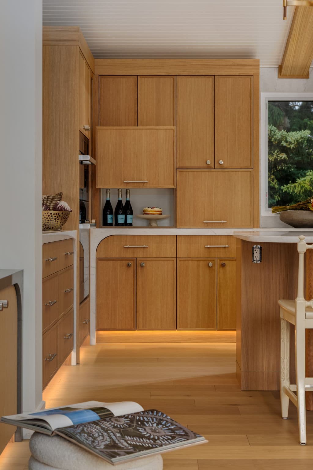 White oak kitchen servery with integrated storage and concealed lighting in the Varal Road renovation by Platinum Build Homes in Varsity, Calgary.
