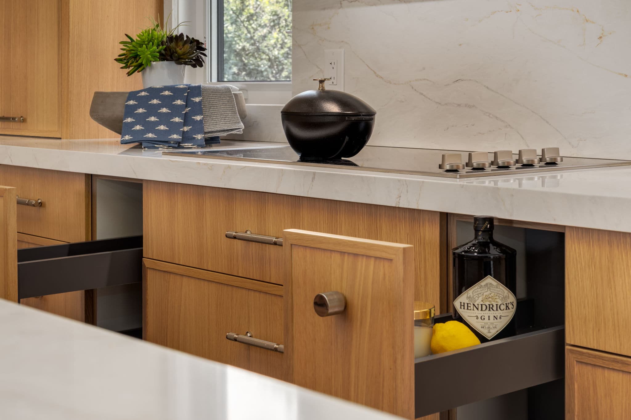 White oak drawers and integrated storage beneath a quartz kitchen worktop in the Varal Road renovation by Platinum Build Homes in Varsity, Calgary.