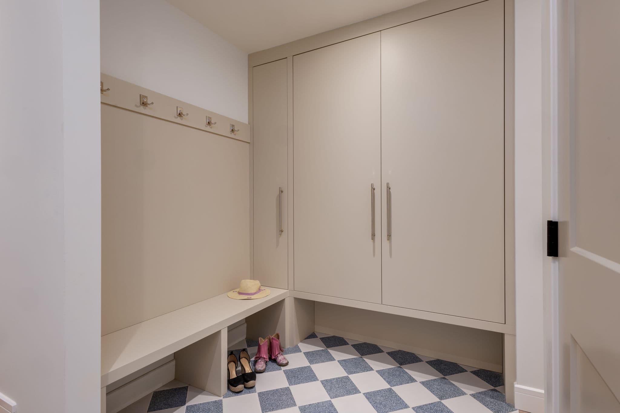 Mudroom with custom storage and checkerboard tile flooring in the Varal Road renovation by Platinum Build Homes in Varsity, Calgary.