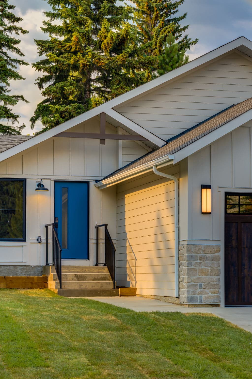 Front entry detail with a blue door, white siding, and stone accents at the completed Varal Road renovation in Varsity, Calgary.