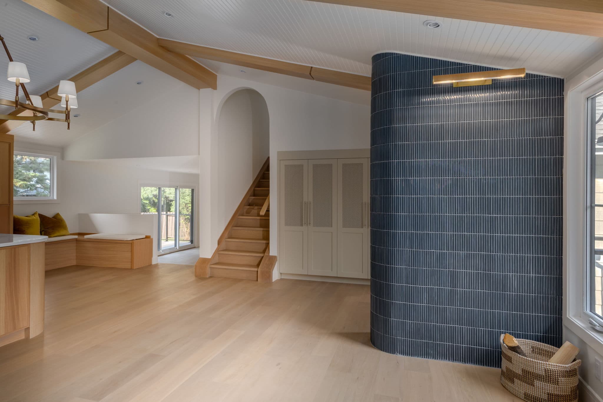 Entry and living area with a curved blue-tile wall, oak beams, and custom storage in the Varal Road renovation by Platinum Build Homes in Varsity, Calgary.